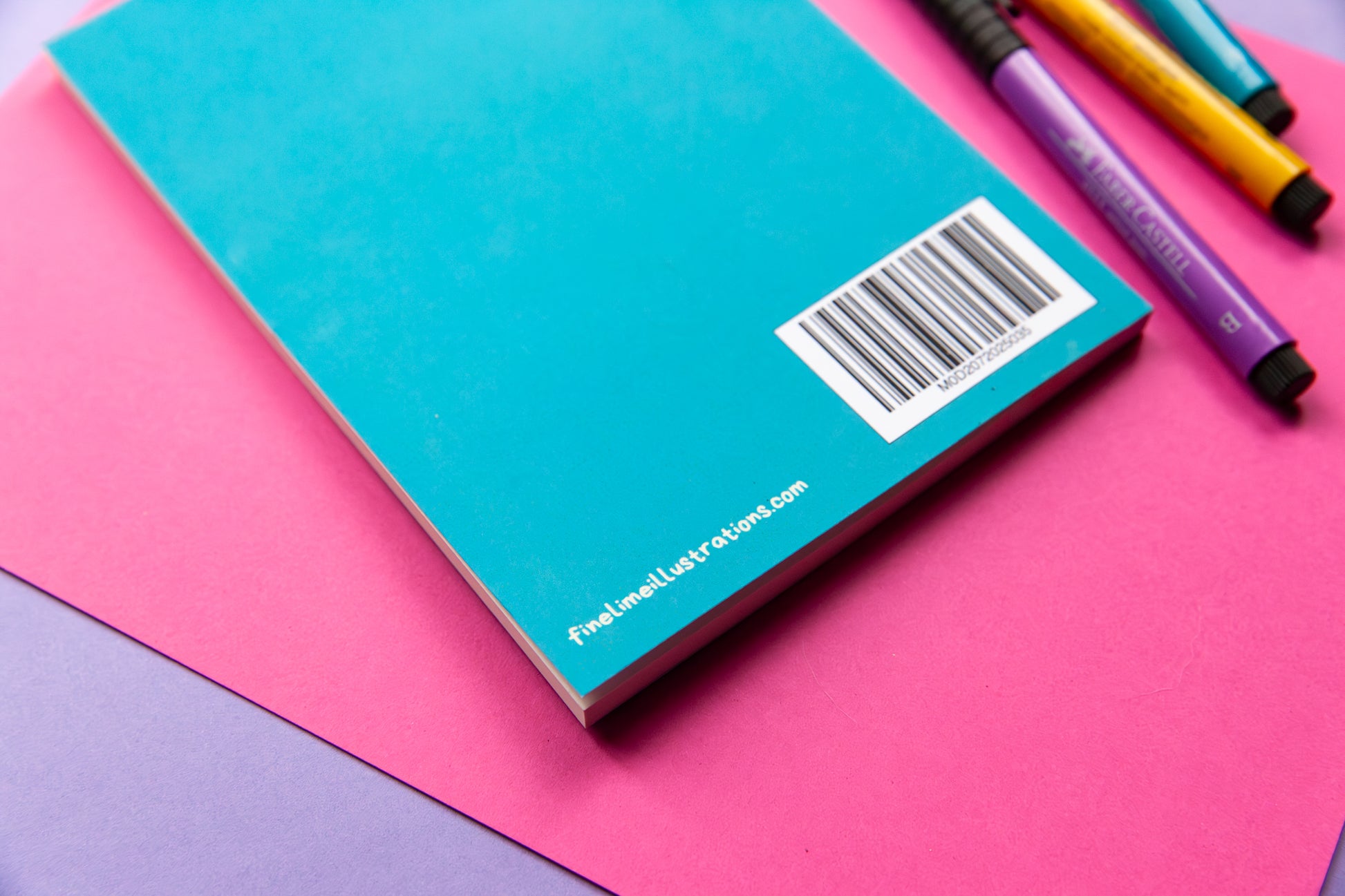 The back cover of a teal notebook showing a bar code and the company website